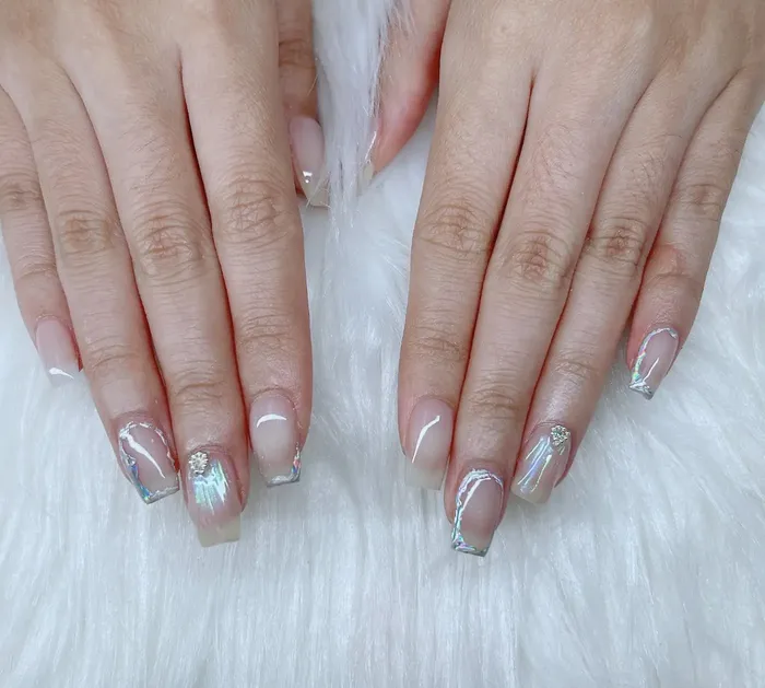 Chrome-outlined nail set with iridescent accents done at Nails Trend